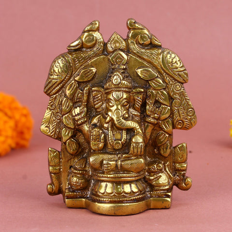 Brass Lord Ganesha idol seated in a traditional pose, adorned with intricate carvings and surrounded by peacock and floral motifs. India’s Largest Pooja Accessories Brand – www.satvikworld.com
